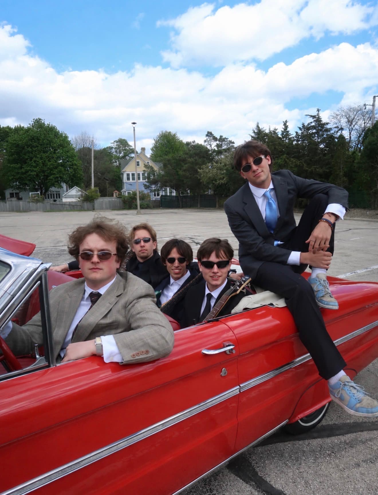 All five members of Blonde with a red convertible